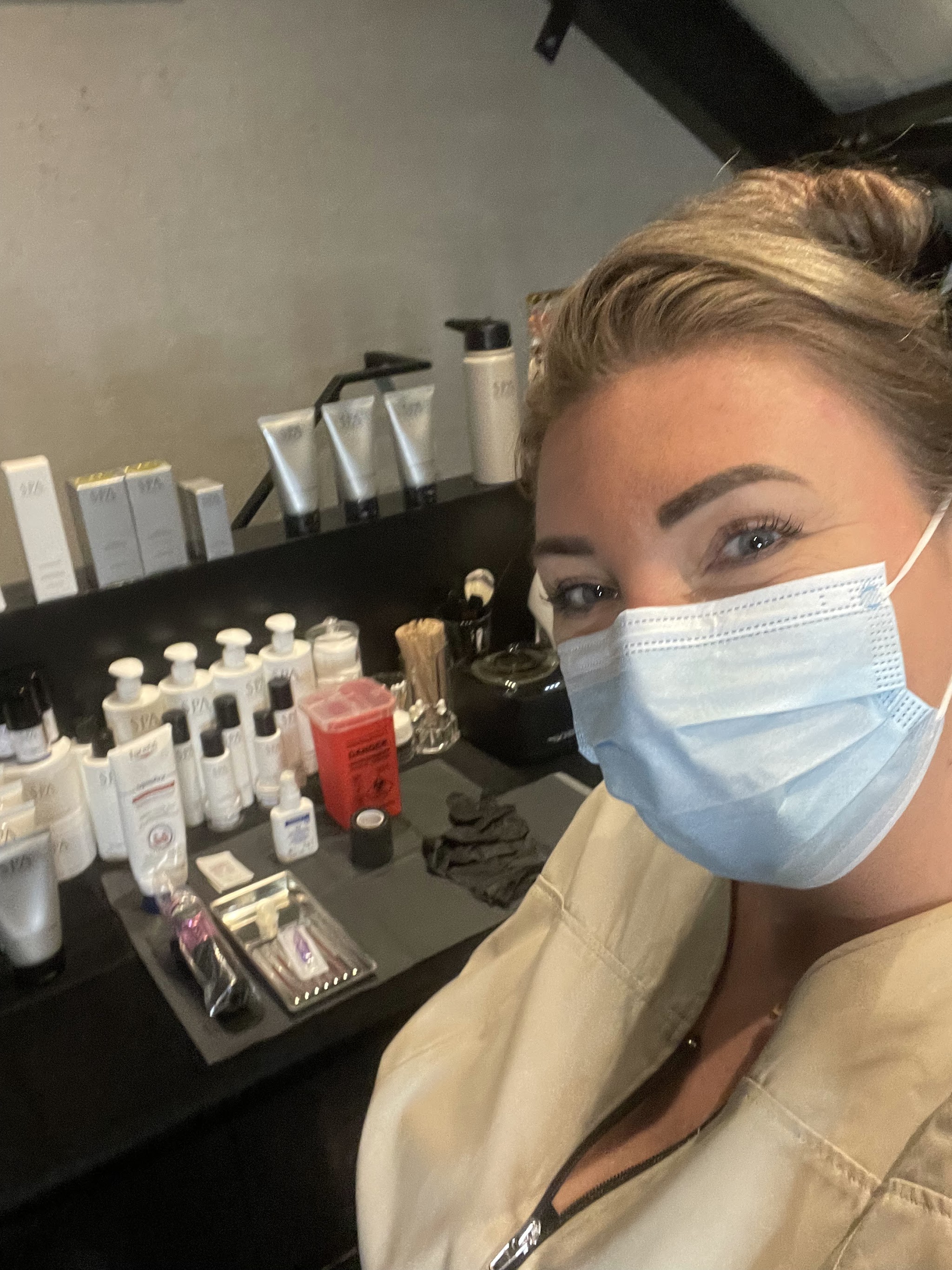 De behandelaar van FIFTY met mondkapje voor de kast met producten in de salon